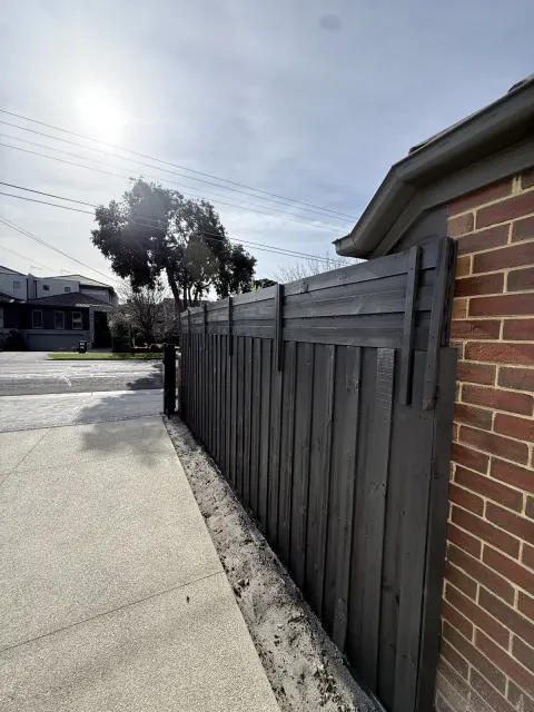Dark timber fence beside brickwork