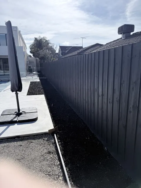 Dark timber boundary fence beside a patio