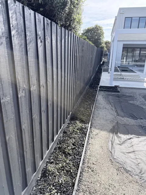 Dark timber fence along a garden boundary